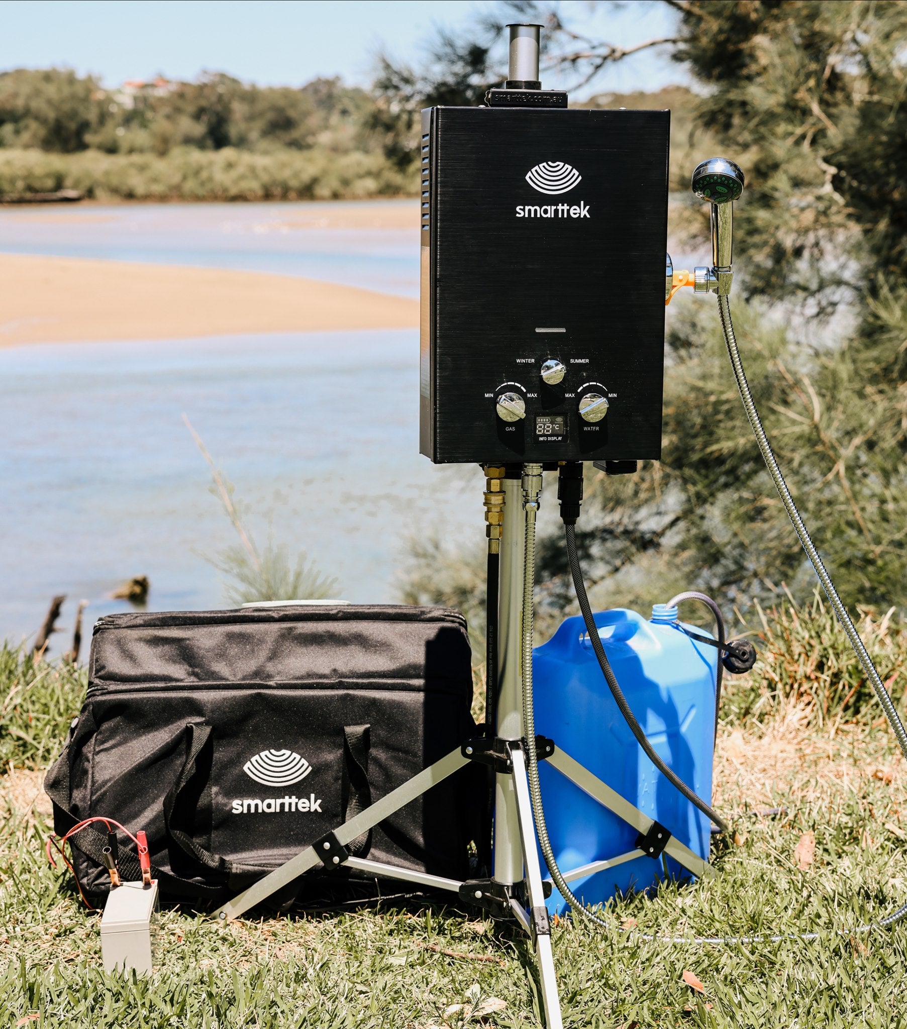 Smarttek Black 4.3LPM portable hot water system set up outdoors with a jerry can and accessories.