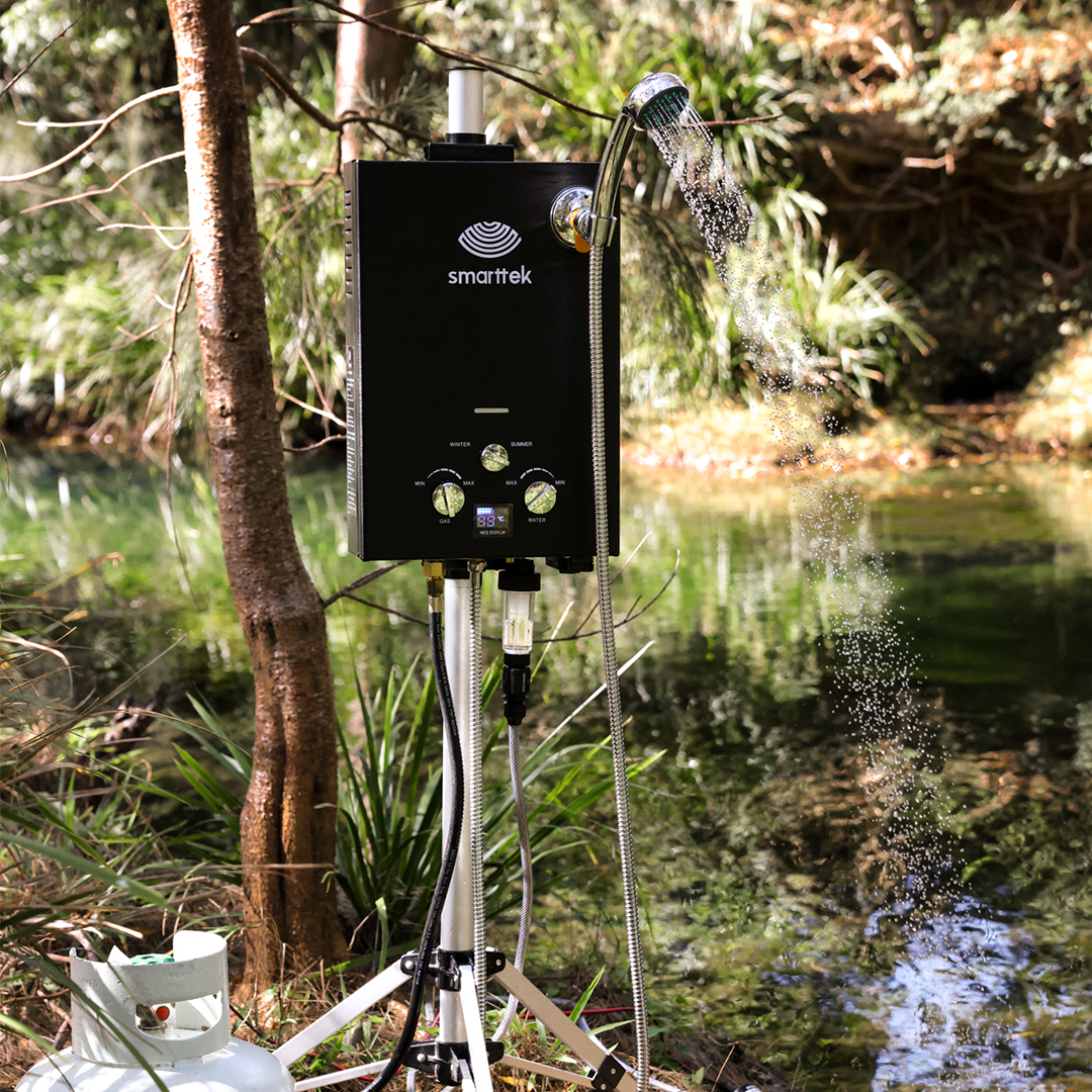 Smarttek Black hot water unit set up outdoors near a creek.
