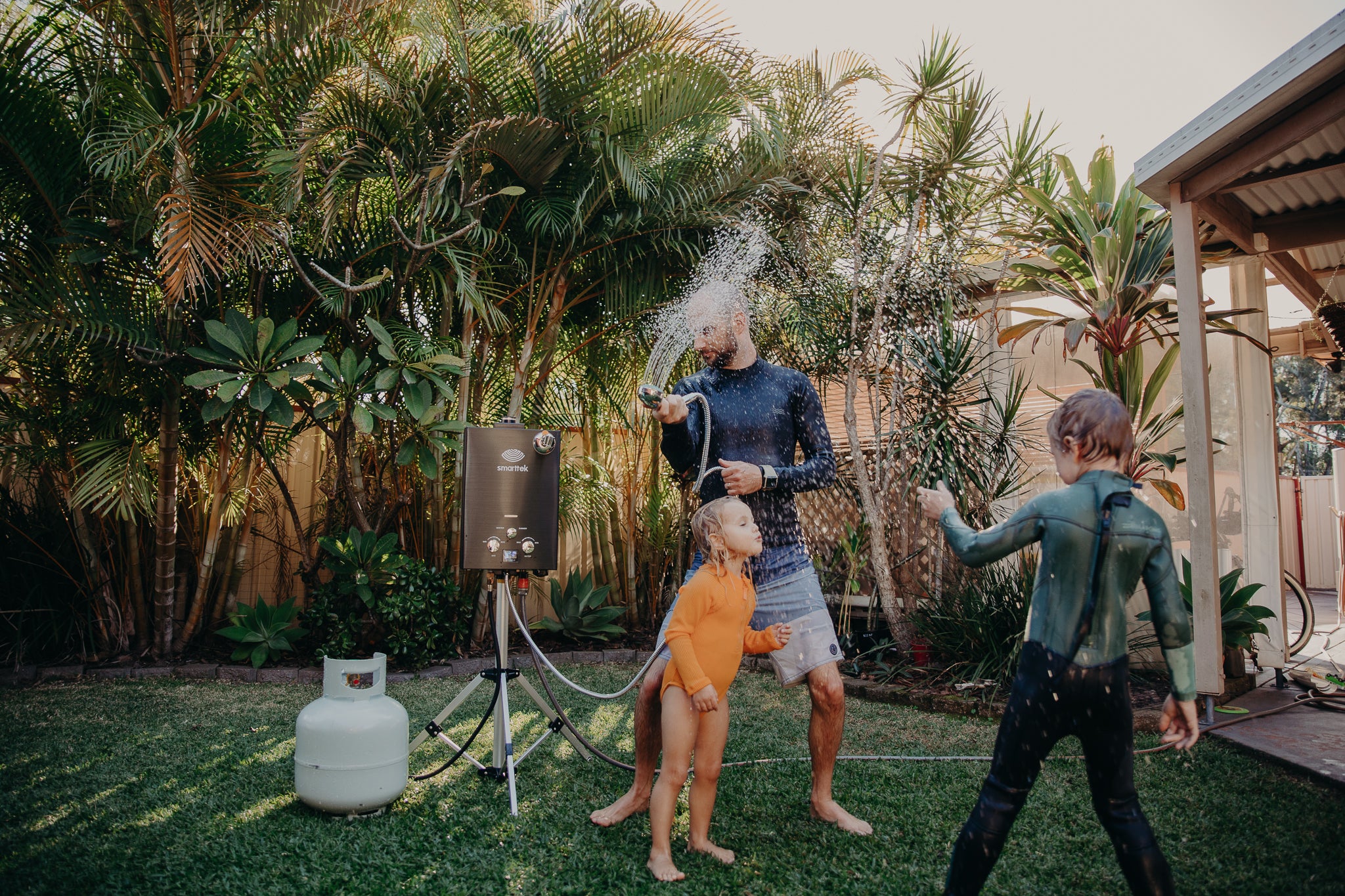 People using a Smarttek Black hot water unit outdoors.