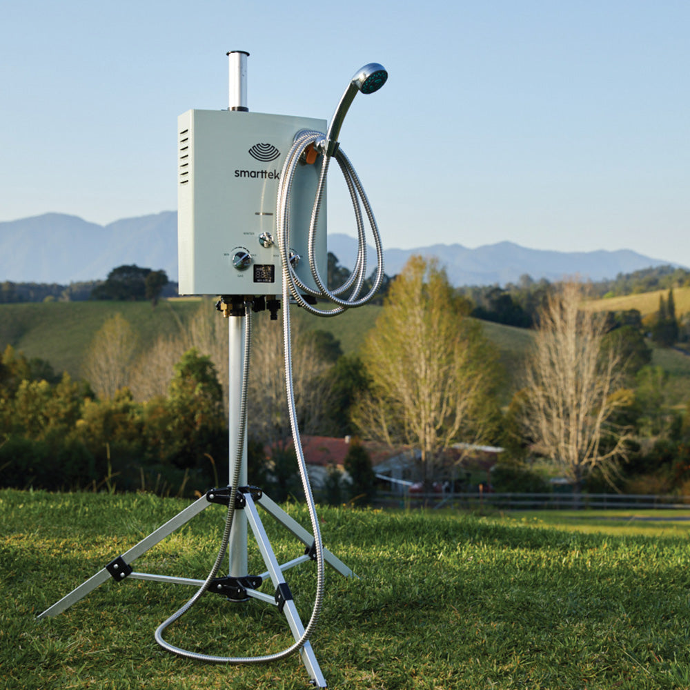 Smarttek hot water system on a tripod with the 5 metre premium shower hose attached at an outdoor campsite.